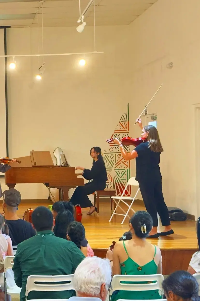 A violinist and a pianist perform for an audience at a Triad Suzuki Academy concert